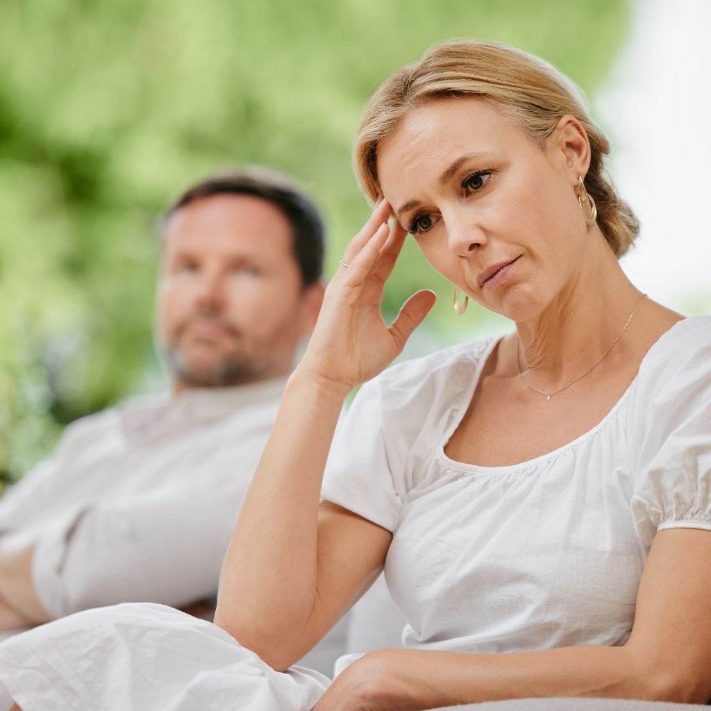 A woman sitting next to another man on the ground.